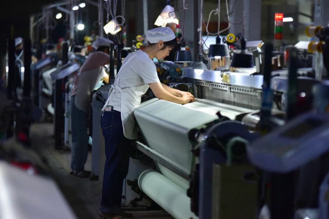 Empleados trabajando en la línea de producción de la empresa Anhui Jingjiu Silk Company en Fuyang, provincia de Anhui, China, el 20 de octubre de 2025. (STR/AFP a través de Getty Images).