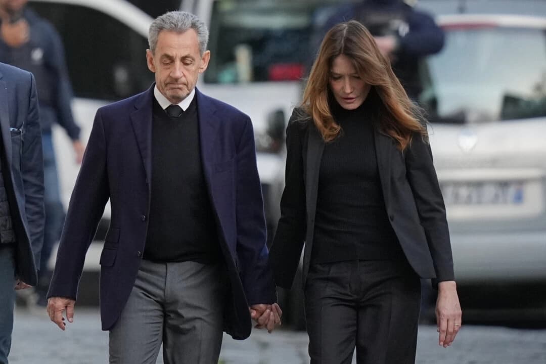 El expresidente francés Nicolas Sarkozy y su esposa, Carla Bruni-Sarkozy, abandonan su domicilio mientras Sarkozy se dirige a la cárcel para cumplir condena por conspiración criminal para financiar su campaña electoral de 2007 con fondos procedentes de Libia, en París, el 21 de octubre de 2025. (Foto AP/Thibault Camus)
