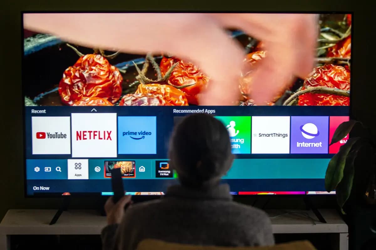 <em>En esta ilustración fotográfica tomada en Toronto el 22 de marzo de 2024, se observa a una persona navegando por el menú de un televisor que muestra iconos de los servicios de streaming Netflix y Amazon Prime. (The Canadian Press/Giordano Ciampini)</em>