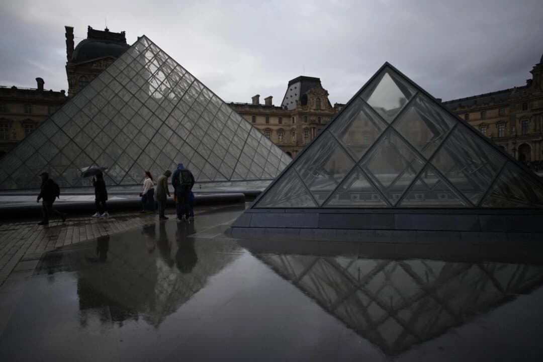 Visitantes recorren el patio del museo del Louvre bajo la lluvia en París, el 27 de octubre de 2025. (Foto: Christophe Ena/AP)