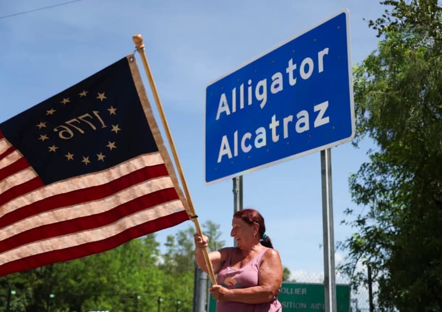 Rana Mourer ondea una bandera estadounidense frente al centro de detención de inmigrantes ilegales apodado "Alligator Alcatraz", en las instalaciones de Dade-Collier Training and Transition en Ochopee, Florida, el 12 de julio de 2025. (Alexandra Rodríguez/AP Photo)