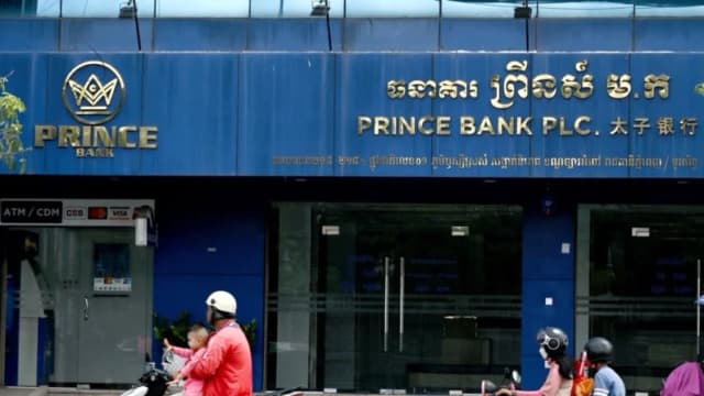 Automovilistas pasan frente a una sucursal del Prince Bank en Phnom Penh, Camboya, el 15 de octubre de 2025. El banco forma parte de Prince Holding Group, un conglomerado multinacional fundado por Chen Zhi que, según el Departamento de Justicia de EE. UU., sirvió de fachada para "una de las mayores organizaciones criminales transnacionales de Asia". (Tang Chhin Sothy/AFP)
