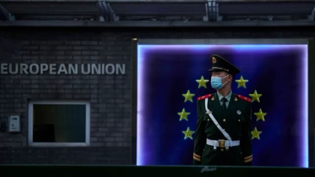 Un miembro de la Policía Armada Popular monta guardia frente a la bandera de la Unión Europea en la Delegación Europea antes de una rueda de prensa de la presidenta de la Comisión Europea, Ursula von der Leyen, en Beijing, el 6 de abril de 2023. (Kevin Frayer/Getty Images)