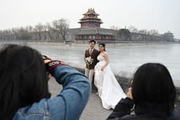 Una pareja posa para las fotos de su boda frente a la Ciudad Prohibida en Beijing, el 11 de febrero de 2025. (Foto de GREG BAKER / AFP) (Foto de GREG BAKER/AFP a través de Getty Images)