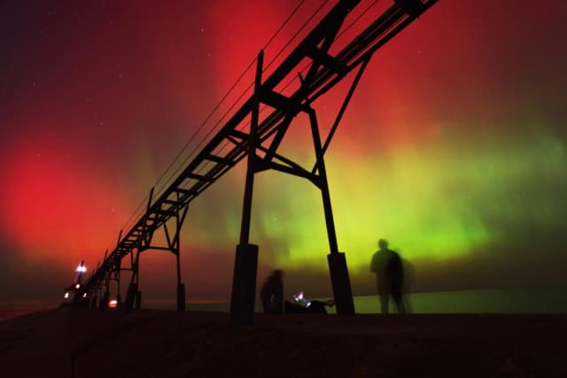 Una aurora boreal, también conocida como luces del norte, ilumina el cielo nocturno frente al lago Michigan y el faro de St. Joseph, el 10 de octubre de 2024, en St. Joseph, Michigan. (Don Campbell/The Herald-Palladium vía AP, archivo)
