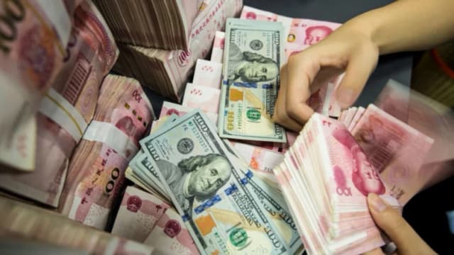 Un empleado bancario chino cuenta billetes de 100 yuanes y dólares estadounidenses en la ventanilla de un banco en Nantong, provincia de Jiangsu, al este de China, el 28 de agosto de 2019. (AFP vía Getty Images)