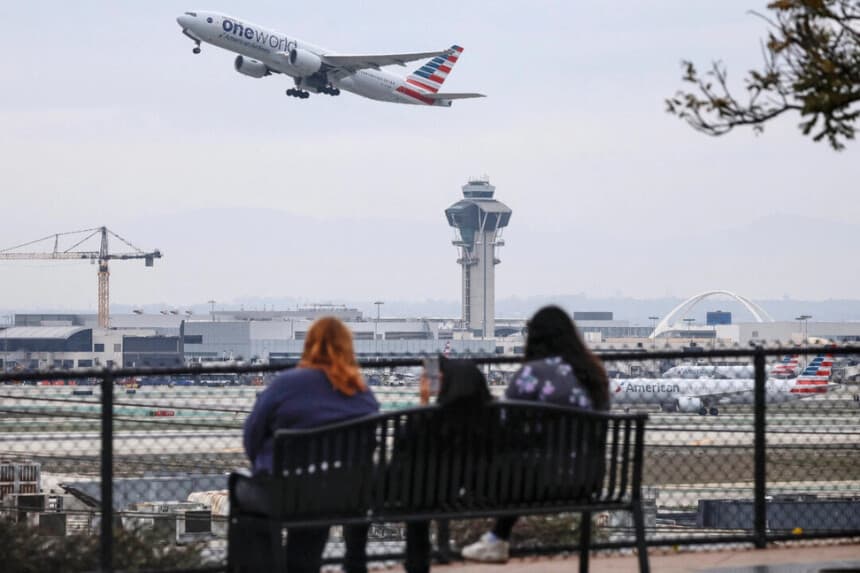 La gente observa desde un mirador cómo despega un avión de American Airlines cerca de la torre de control del tráfico aéreo del Aeropuerto Internacional de Los Ángeles (LAX) en Los Ángeles el 12 de noviembre de 2025. (Mario Tama/Getty Images)