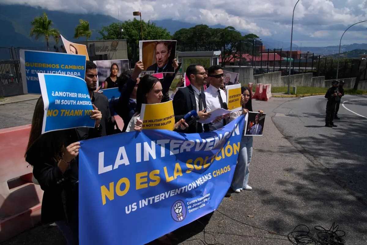 Gabriel Cabrera, presidente del Centro Juvenil Venezolano para la Democracia, hace una declaración frente a la embajada de Estados Unidos con miembros de la organización que sostienen carteles en los que se lee en español "La intervención no es la solución", en referencia a los buques de guerra estadounidenses que operan en el Caribe, en Caracas, Venezuela, el 27 de octubre de 2025. (AP Photo/Ariana Cubillos)