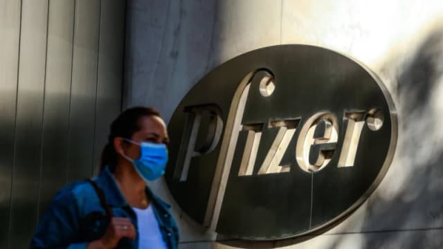 Una mujer usa mascarilla mientras pasa frente a la sede mundial de Pfizer en Nueva York el 9 de noviembre de 2020. Las acciones de Pfizer subieron el 9 de noviembre de 2020 antes de la apertura de Wall Street, tras el anuncio de la compañía de que su vacuna tiene una eficacia del 90 % contra las infecciones por COVID-19. La noticia alegró a los mercados de todo el mundo, especialmente ante el aumento repentino de casos de coronavirus, que obliga a millones de personas a volver al confinamiento. (Foto de KENA BETANCUR/AFP vía Getty Images)

