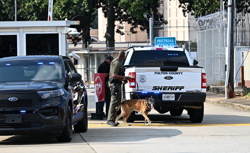 Un agente de policía camina con su perro K-9 fuera de la cárcel del condado de Fulton en Atlanta, Georgia, el 24 de agosto de 2023. (Foto de CHANDAN KHANNA / AFP) (Foto de CHANDAN KHANNA/AFP a través de Getty Images)