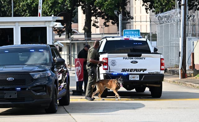 Un agente de policía camina con su perro K-9 fuera de la cárcel del condado de Fulton en Atlanta, Georgia, el 24 de agosto de 2023. (Foto de CHANDAN KHANNA / AFP) (Foto de CHANDAN KHANNA/AFP a través de Getty Images)