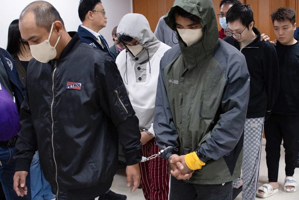 Ciudadanos chinos (al fondo, der.) y sus presuntos cómplices filipinos (izq.), arrestados por presunto espionaje, son escoltados por agentes de la Oficina Nacional de Investigaciones (NBI) tras una conferencia de prensa en la oficina de la NBI en Manila el 25 de febrero de 2025. (Ted Aljibe/AFP vía Getty Images)