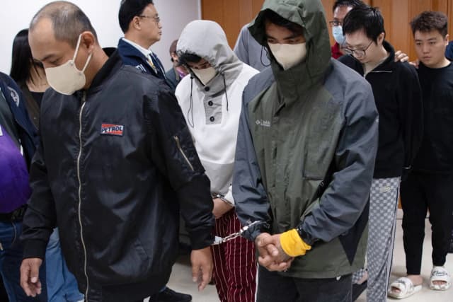 Ciudadanos chinos (al fondo, der.) y sus presuntos cómplices filipinos (izq.), arrestados por presunto espionaje, son escoltados por agentes de la Oficina Nacional de Investigaciones (NBI) tras una conferencia de prensa en la oficina de la NBI en Manila el 25 de febrero de 2025. (Ted Aljibe/AFP vía Getty Images)