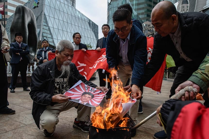 Manifestantes queman carteles con la imagen del primer ministro japonés, Shinzo Abe, y la bandera imperial japonesa de la época de la guerra frente a la embajada japonesa en Hong Kong el 13 de diciembre de 2017, para conmemorar los 80 años de la masacre perpetrada por las tropas japonesas en la ciudad china de Nanjing durante la guerra. (ANTHONY WALLACE/AFP a través de Getty Images) 