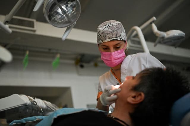 Ornella Sol Fritzler, estudiante de odontología, examina a un paciente en Buenos Aires el 18 de septiembre de 2024. (Foto de LUIS ROBAYO / AFP) (Foto de LUIS ROBAYO/AFP a través de Getty Images)