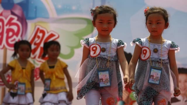 Un par de gemelas desfilan por la pasarela durante el Concurso Provincial de Talentos de Gemelas de Jiangsu, en Nanjing, provincia de Jiangsu, China, el 4 de mayo de 2006. (Fotos de China/Getty Images)