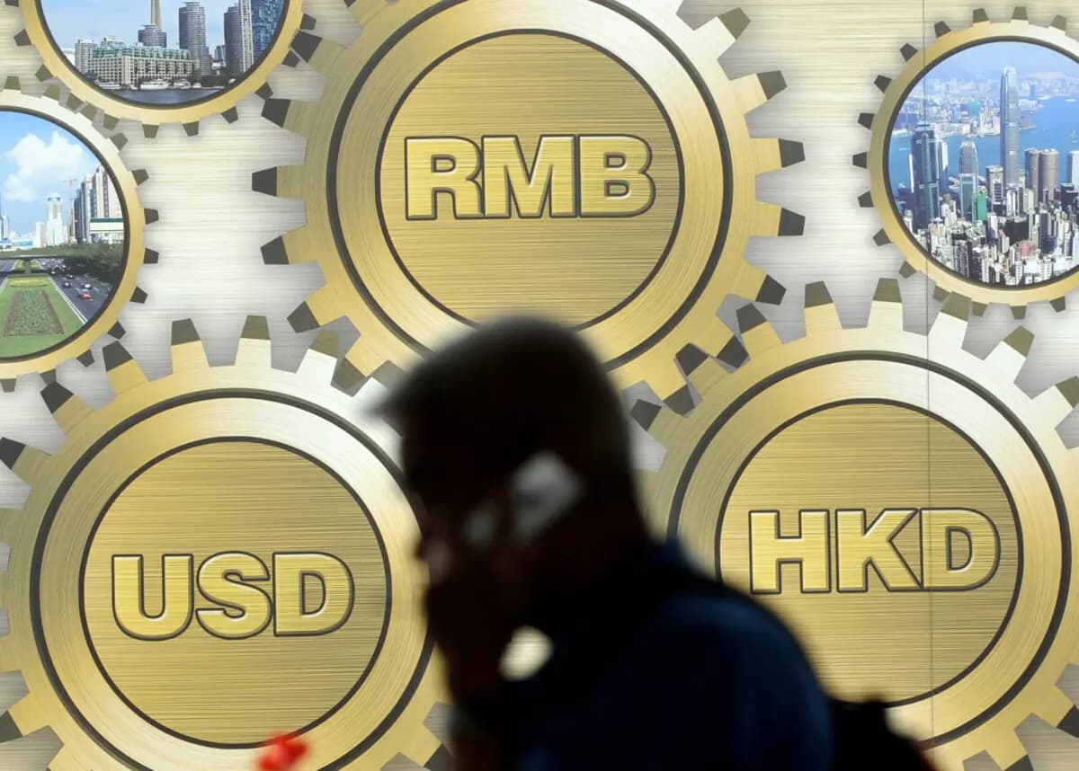 Un peatón pasa junto a una valla publicitaria que muestra los símbolos del yuan chino (arriba en el centro), el dólar de Hong Kong (derecha) y el dólar estadounidense en un edificio de Hong Kong el 21 de marzo de 2009. (Ted Aljibe/AFP a través de Getty Images).