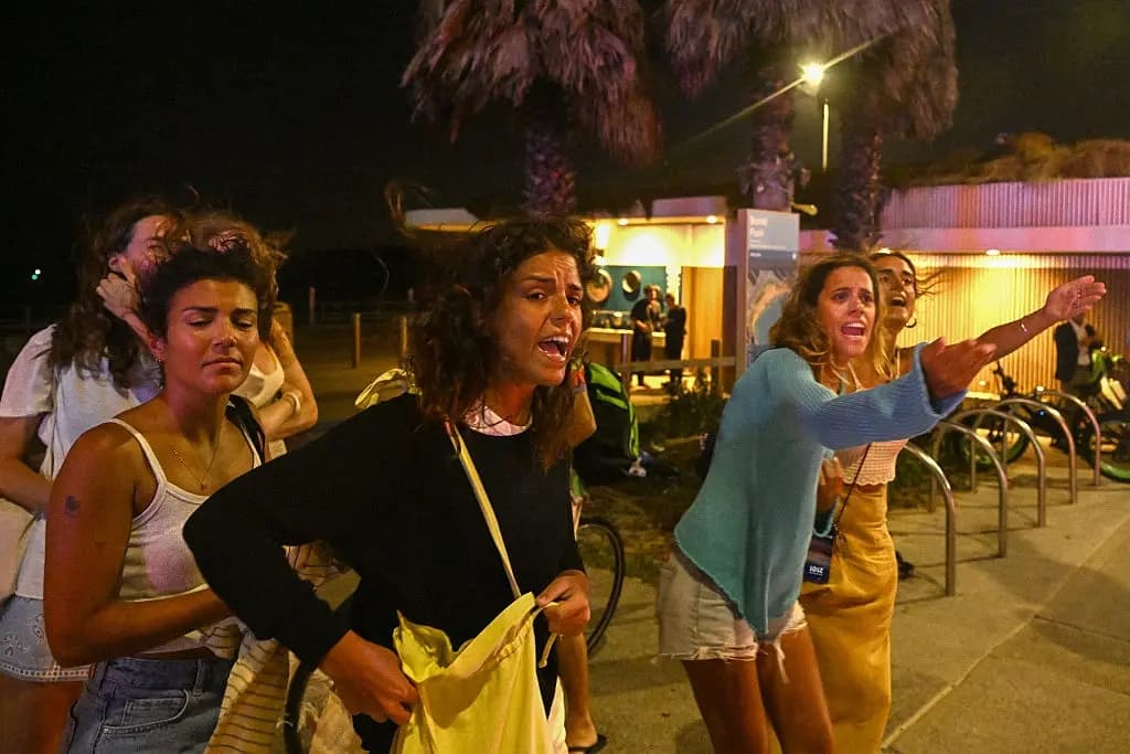 Jóvenes reaccionan al abandonar el lugar del tiroteo en la playa de Bondi, en Sídney, el 14 de diciembre de 2025. (Saeed Khan/AFP a través de Getty Images)