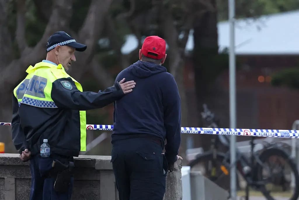Un agente de policía consuela a una persona de la comunidad judía en el lugar del tiroteo en Bondi Beach, Sídney, el 15 de diciembre de 2025. (DAVID GRAY / AFP a través de Getty Images)