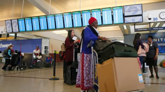 Pasajeros de una aerolínea esperan para facturar en el mostrador de United Airlines al día siguiente de un corte de electricidad causado por un incendio en el Aeropuerto Internacional Hartsfield-Jackson de Atlanta, Georgia, el 18 de diciembre de 2017. / AFP PHOTO / TAMI CHAPPELL (El crédito de la foto debe leer TAMI CHAPPELL/AFP a través de Getty Images)