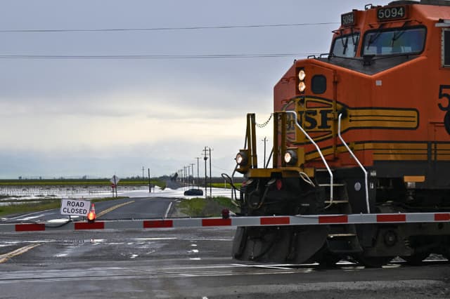 Una locomotora de BNSF arrastra vagones de tren por las inundaciones del Valle Central durante una tormenta invernal en el condado de Tulare, cerca de Allensworth, California, el 22 de marzo de 2023. (PATRICK T. FALLON/AFP a través de Getty Images)