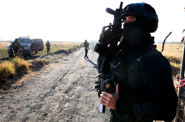 Miembros de la Fiscalía General de México vigilan la entrada a la carretera de un presunto «centro de reclutamiento» del crimen organizado en la comunidad de La Estanzuela, en el municipio de Tehuchitlán, estado de Jalisco, México, el 28 de marzo de 2025. (ULISES RUIZ/AFP vía Getty Images)