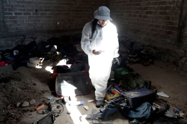 Una mujer registra ropa y zapatos encontrados en el Rancho Izaguirre, en la comunidad de La Estanzuela, donde el colectivo "Guerreros Buscadores" localizó tres crematorios humanos mientras buscaba a sus familiares en Teuchitlán, Jalisco, México, el 5 de marzo de 2025. (ULISES RUIZ/AFP vía Getty Images)