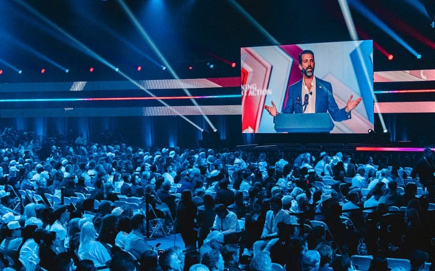 Una pantalla muestra a Donald Trump Jr. hablando en el escenario durante la conferencia anual AmericaFest de Turning Point en Phoenix, Arizona, el 21 de diciembre de 2025. (Olivier Touron/AFP vía Getty Images)