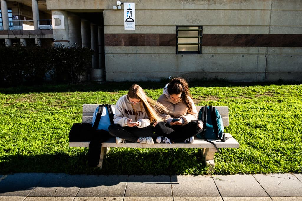 Jóvenes adolescentes y estudiantes de secundaria sentadas en un banco durante el recreo del instituto y consultando sus teléfonos o smartphones y redes sociales una al lado de la otra en el Lycee Aristide Maillol de Perpiñán, en el departamento de Pirineos Orientales, en el sur de Francia, el 14 de noviembre de 2024. (Foto de Jc Milhet / Hans Lucas / Hans Lucas vía AFP) (Foto de JC MILHET/Hans Lucas/AFP vía Getty Images)
