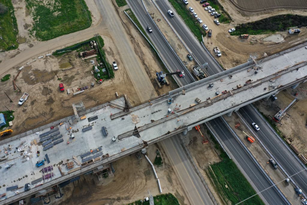 Una imagen aérea muestra a los trabajadores de la construcción construyendo el viaducto de Hanford sobre la autopista 198 y los campos agrícolas, como parte del proyecto de transporte ferroviario de alta velocidad de California (CAHSR) en Hanford, California, el 12 de febrero de 2025. El viaducto de Hanford es la estructura ferroviaria de alta velocidad más grande del Valle Central, con más de 6000 pies de longitud. (Foto de Patrick T. Fallon / AFP) (Foto de PATRICK T. FALLON/AFP a través de Getty Images)