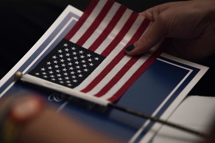 Una bandera estadounidense y un formulario de solicitud de visado H-1B, en esta ilustración del 22 de septiembre de 2025. (Dado Ruvic/Ilustración/Reuters).