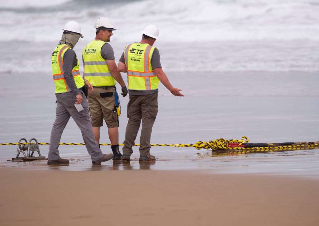 Operarios conversan mientras instalan un cable submarino de fibra óptica en la playa de Arrietara, cerca del pueblo vasco español de Sopelana, el 13 de junio de 2017. (Foto de ANDER GILLENEA / AFP) (Foto de ANDER GILLENEA/AFP a través de Getty Images)
