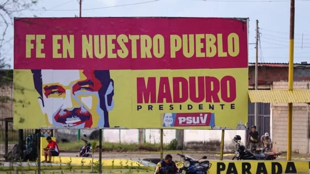 Un motociclista descansa bajo una pancarta en apoyo al presidente venezolano Nicolás Maduro en las afueras de la refinería El Palito en Puerto Cabello, Venezuela, el 18 de diciembre de 2025. (Jesús Vargas/Getty Images)