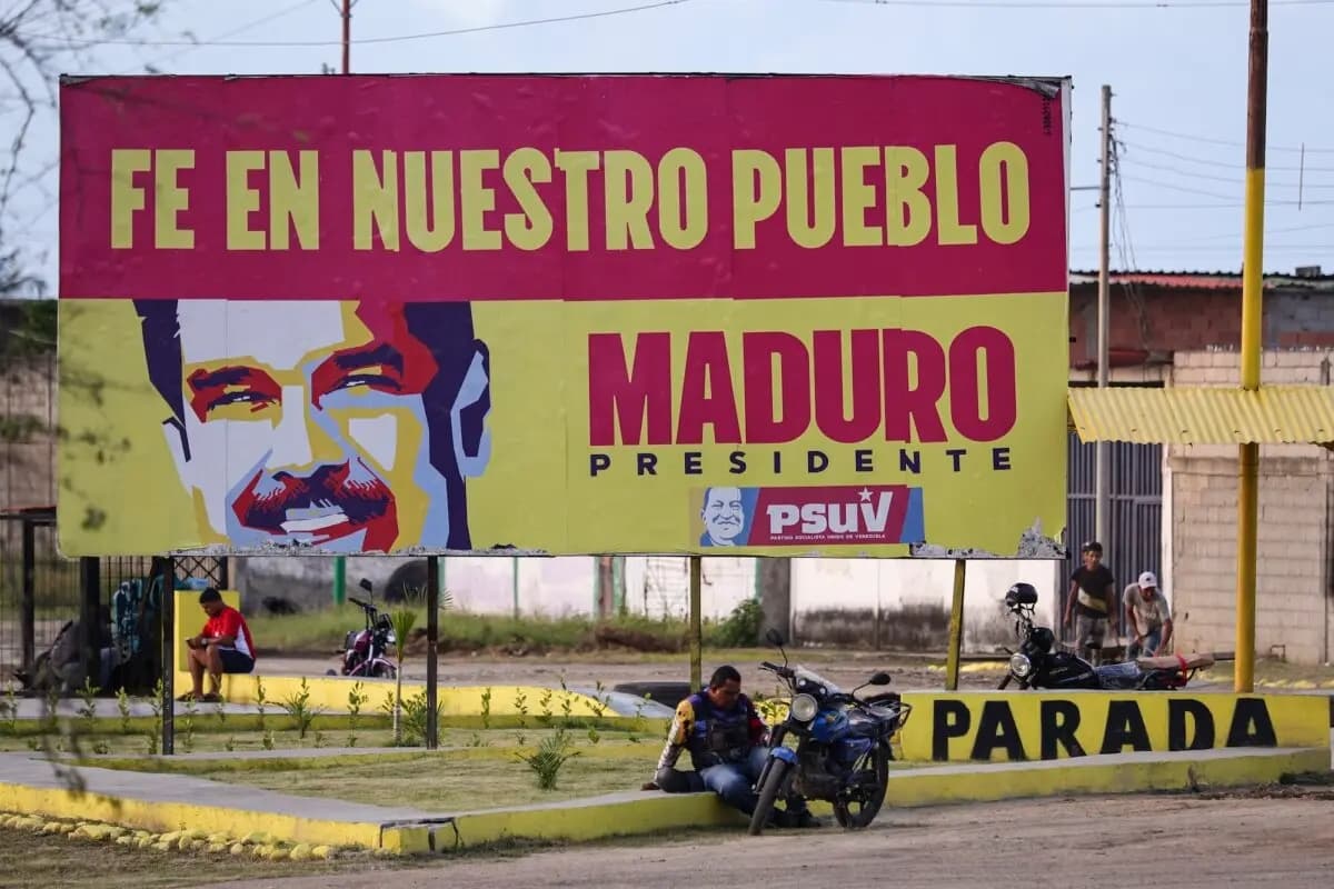 Un motociclista descansa bajo una pancarta en apoyo al presidente venezolano Nicolás Maduro en las afueras de la refinería El Palito en Puerto Cabello, Venezuela, el 18 de diciembre de 2025. (Jesús Vargas/Getty Images)