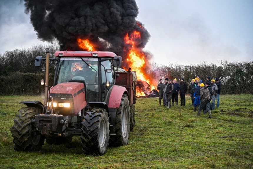 Los agricultores prenden fuego mientras participan, con sus vehículos, en un bloqueo de la entrada de la autopista A84 en Poilley, Francia, el 5 de enero de 2026, que forma parte de una serie de acciones convocadas en la región por el sindicato francés de agricultores Coordination Rural. (Damien Meyer/AFP a través de Getty Images).