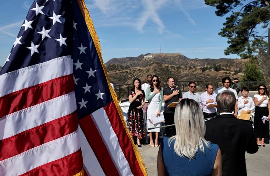 : Los nuevos ciudadanos estadounidenses recitan el juramento de lealtad durante una ceremonia especial de naturalización en la terraza del letrero de Hollywood, en el histórico Observatorio Griffith, el 21 de octubre de 2024 en Los Ángeles, California. (Mario Tama/Getty Images)