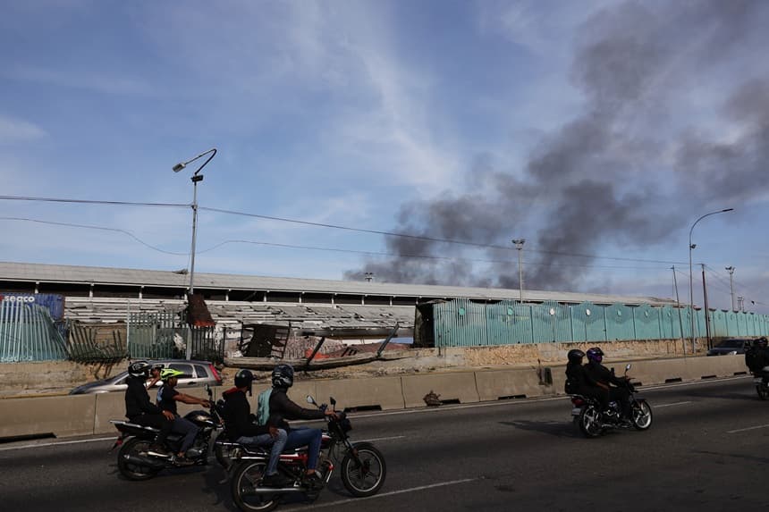 La gente conduce por una autopista pasando por una zona dañada del puerto de La Guaira después de que se escucharan explosiones y aviones volando a baja altura el 3 de enero de 2026 en La Guaira, Venezuela. (Jesús Vargas/Getty Images)