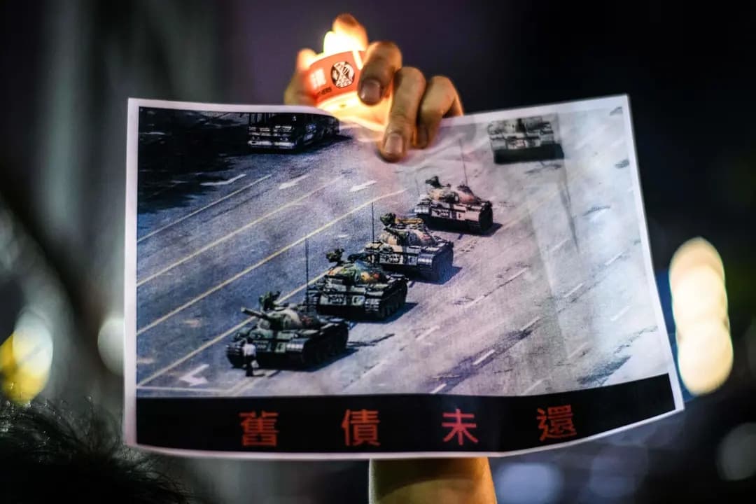 Un hombre sostiene un cartel del "hombre del tanque" frente a los tanques en la plaza de Tiananmen de Beijing el 5 de junio de 1989, durante una vigilia con velas en Hong Kong el 4 de junio de 2020. (Anthony/AFP vía Getty Images)