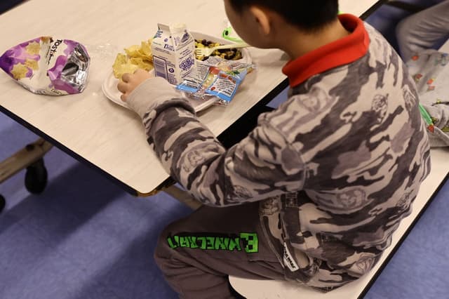 Un estudiante come una comida vegana servida para el almuerzo (con leche como bebida) en la escuela Yung Wing P.S. 124 el 4 de febrero de 2022 en la ciudad de Nueva York. (Michael Loccisano/Getty Images)