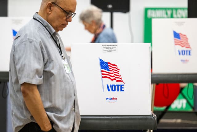 Los trabajadores electorales de la Junta Electoral de Maryland pasan junto a cabinas vacías durante las elecciones primarias del estado de Maryland en un colegio electoral de Annapolis, Maryland, el 14 de mayo de 2024. (Foto de Jim WATSON / AFP) (Foto de JIM WATSON/AFP vía Getty Images)