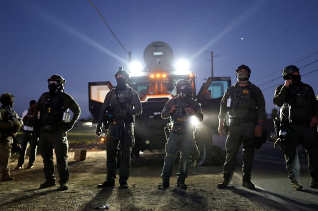 Agentes federales bloquean a personas que protestan contra una redada migratoria del ICE en una granja de cannabis con licencia cercana, el 10 de julio de 2025, cerca de Camarillo, California. Los manifestantes se enfrentaron durante horas a los agentes federales frente a la granja, situada en la comunidad agrícola del condado de Ventura. Un juez federal de Los Ángeles dictará sentencia el viernes sobre una orden de restricción temporal que limitaría las operaciones de control migratorio en la zona. (Foto de Mario Tama/Getty Images).