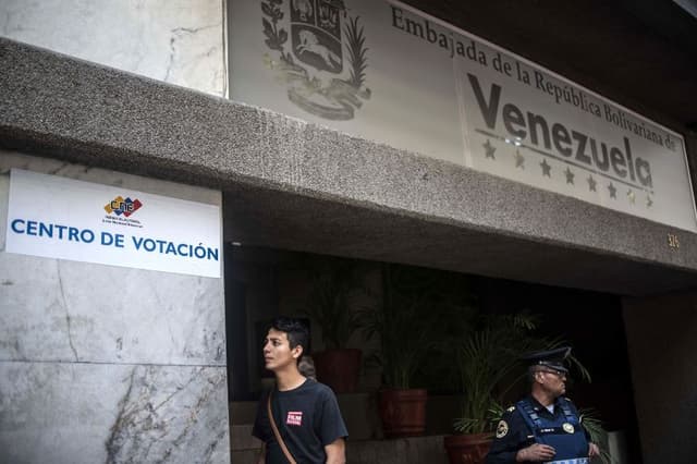 Un agente de policía monta guardia frente a la embajada venezolana en Ciudad de México, donde se instaló un centro de votación, mientras miembros de la comunidad venezolana en México protestan contra las elecciones presidenciales en su país, el 20 de mayo de 2018. (PEDRO PARDO/AFP a través de Getty Images)