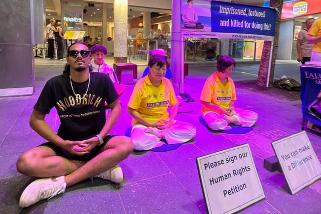 Los transeúntes se unen a una meditación con practicantes locales de Falun Gong en Cavill Mall, en Gold Coast, Australia, el 2 de enero de 2026. (Cortesía de Maryann Leatham).