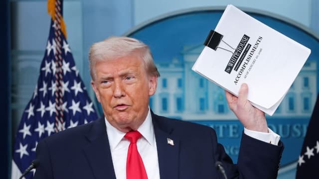 El presidente de los Estados Unidos, Donald Trump, muestra una pila de papeles con la etiqueta "Logros de la Casa Blanca" al llegar a una rueda de prensa en la sala James S. Brady de la Casa Blanca el 20 de enero de 2026 en Washington, D.C. (Kevin Dietsch/Getty Images)