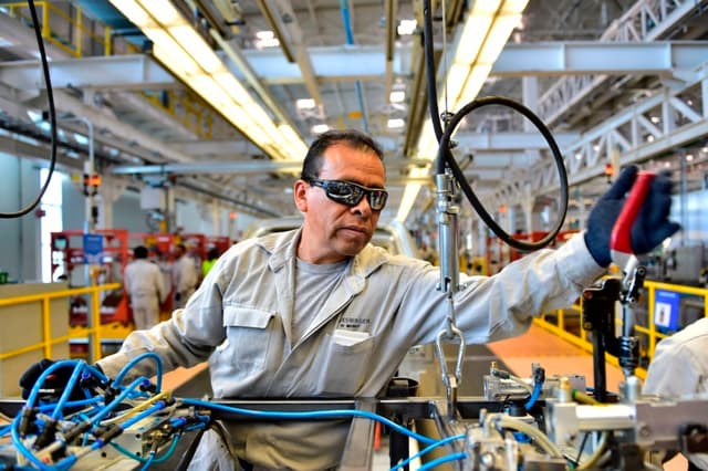 Aquí tienes la traducción al español, manteniendo el formato de pie de foto periodístico:

"Empleados trabajan en la línea de ensamblaje del modelo Tiguan, en la planta de automóviles de Volkswagen en Puebla, en el centro de México, el 16 de marzo de 2018.(PEDRO PARDO/AFP via Getty Images)