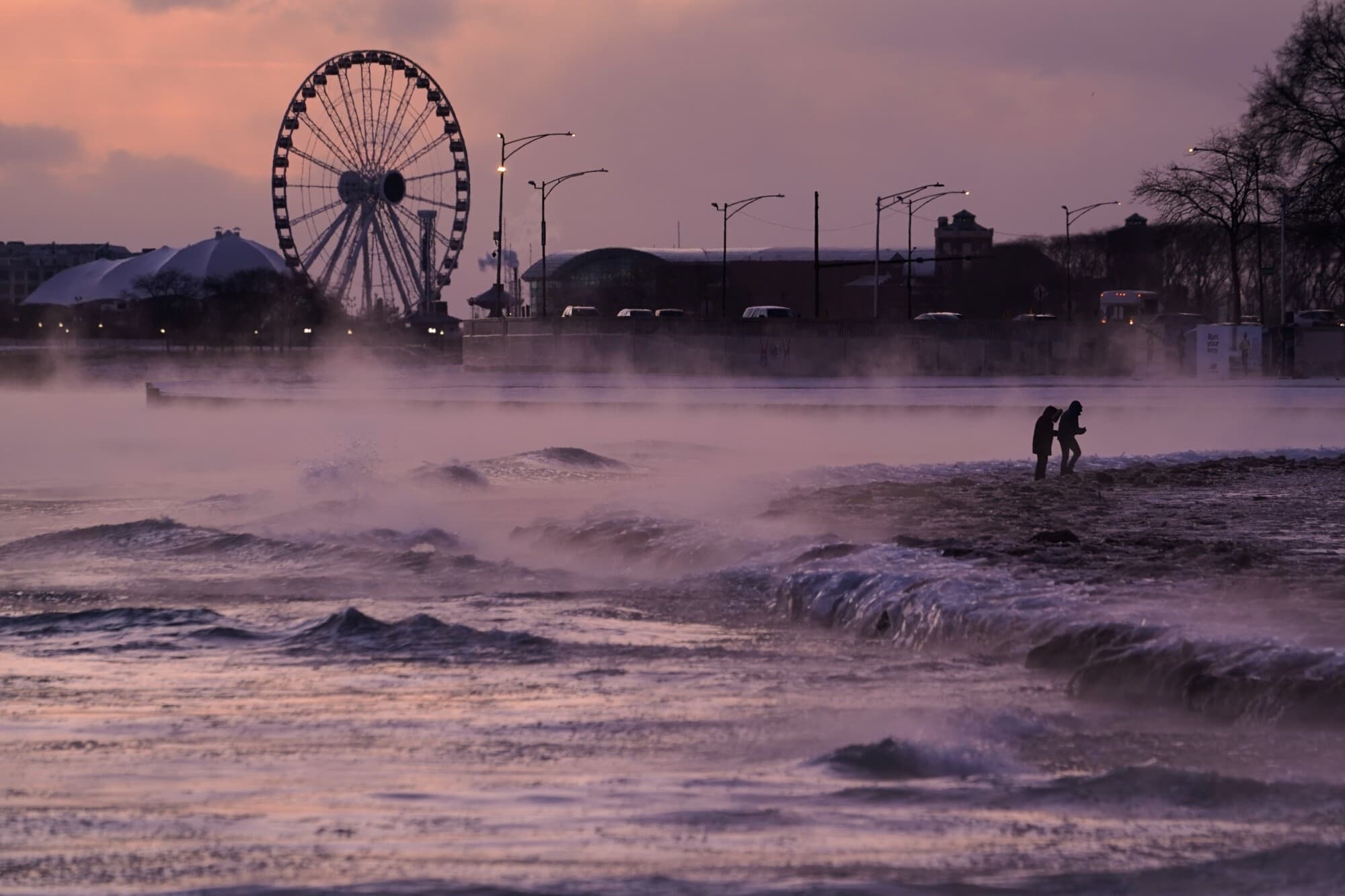 La gente camina por una playa cubierta de hielo a lo largo de la orilla del lago Michigan en Chicago el 23 de enero de 2026. (Kiichiro Sato/AP Photo)