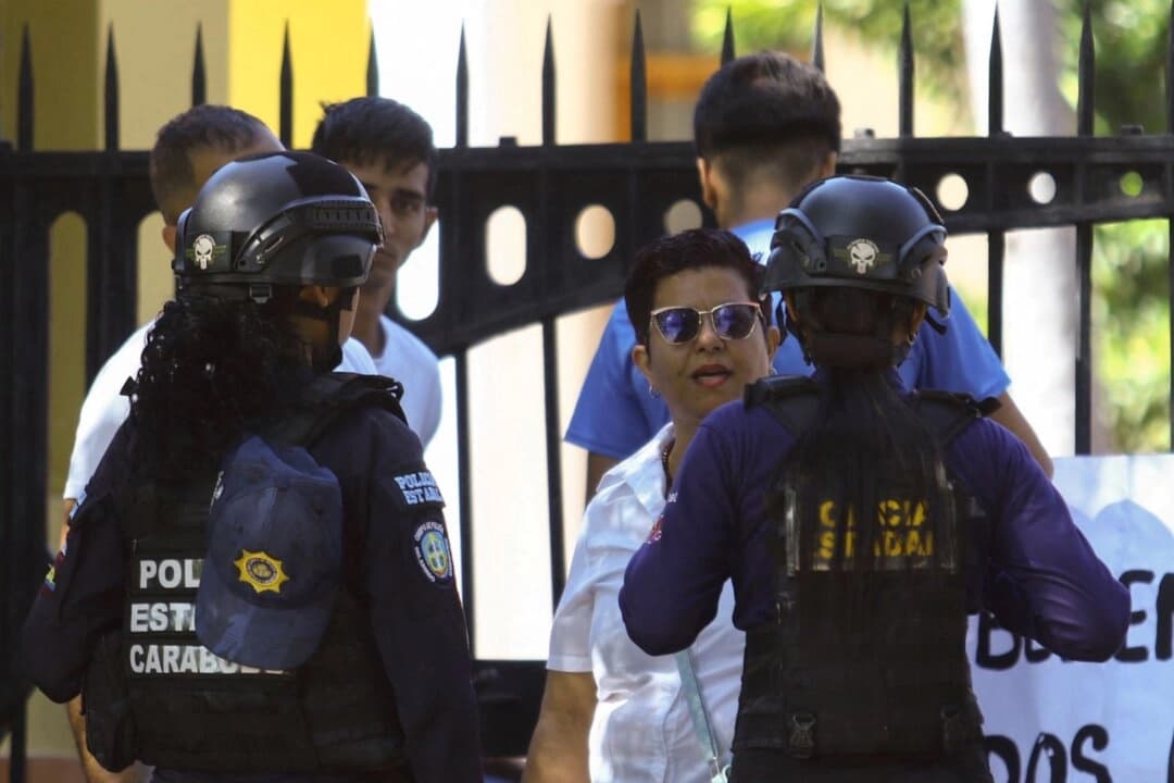 Un oficial de policía habla con el familiar de un preso político durante una protesta apoyada por estudiantes universitarios que exigen su liberación frente a la rectoría de la Universidad de Carabobo, en medio de las liberaciones de presos por parte del régimen venezolano tras la captura de Nicolás Maduro por parte de Estados Unidos, en Valencia, Venezuela, el 23 de enero de 2026. (Juan Carlos Hernández/Reuters)