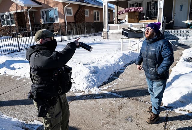 Un observador se enfrenta a un agente del ICE mientras llaman a la puerta de una residencia el 28 de enero de 2026 en Minneapolis, Minnesota. (Stephen Maturen/Getty Images)