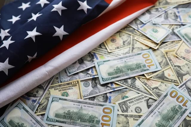 La bandera de EE. UU. y varios dólares norteamericanos. (alexkich/Shutterstock)