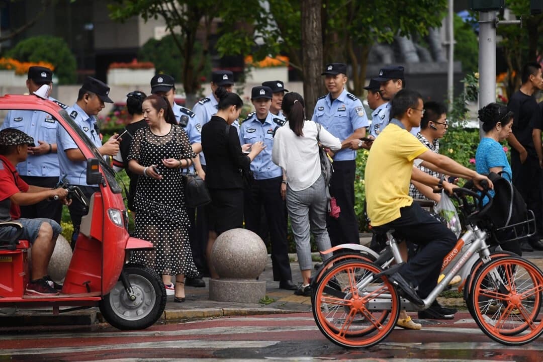 La policía comprueba la identificación de los transeúntes mientras busca a demandantes cerca de la Comisión Reguladora Bancaria de China en Beijing, el 6 de agosto de 2018. (Greg Baker/AFP a través de Getty Images)